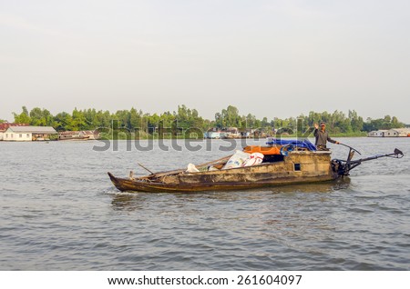 CHAU DOC, VIETNAM, JANUARY 3, 2013: Local man transports merchandise by boat on Hau River (Bassac River) in Chau Doc in Mekong Delta