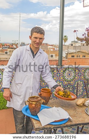 MARRAKESH, MOROCCO, APRIL 3, 2015: Restaurant at Jemaa el-Fnaa square - the waiter serves lamb and beef meat braised in clay pots