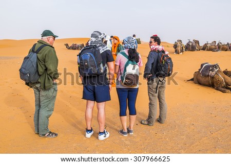 MERZOUGA, MOROCCO, APRIL 13, 2015: Tourists waits for a camel ride on sand dunes of Erg Chebbi