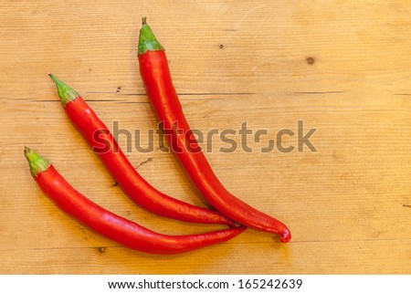 Three long red chills on a rustic wooden table