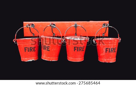 Four vintage battered red fire buckets hanging on hooks - isolated on black