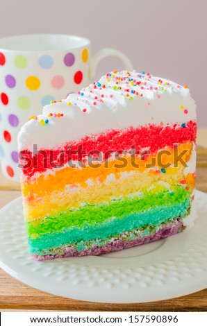 Rainbow cake with rainbow cup on the wood table
