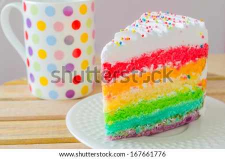 Rainbow cake with rainbow cup on the wood table