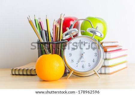 Back to school , note book , clock , pencil , apple on wood table