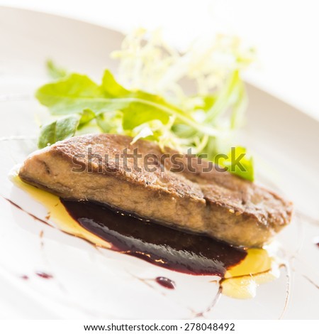 Grilled foie gras with sweet sauce in white dish - selective focus point