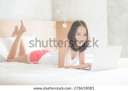 Young asian woman using computer in bedroom - vintage film tone effect and light filter processing