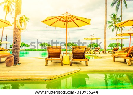 Umbrella chair in hotel pool resort with sunset - Vintage filter and sunflare light filter processing
