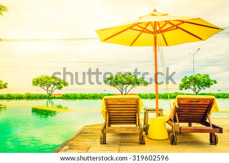 Umbrella chair in hotel pool resort with sunset - Vintage filter and sunflare light filter processing