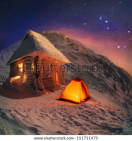 Traveling through the winter mountains, bold and romantic people can find shelter in the alpine huts Cold night on the mountain top, under the stars