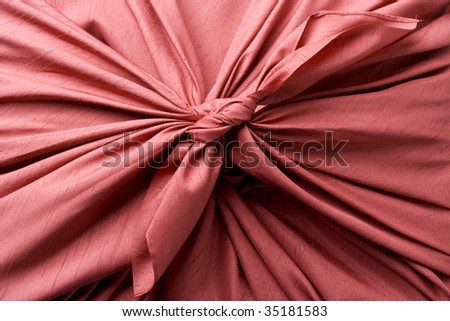 SEASONAL IMAGE-close-up shot of a gift box wrapped with red Japanese traditional cloth ; FUROSHIKI