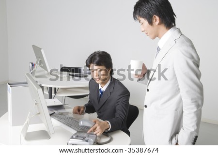 BUSINESS IMAGE-two  businessmen ; one is drinking a cup of coffee and the other is trying to make a phone call