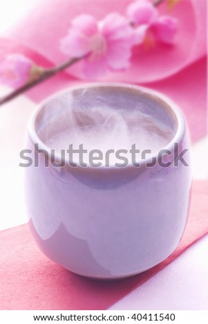 Pink peach flower and sweet drink made from fermented rice in the teacup.