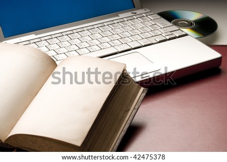 Old book opened to blank pages by laptop computer