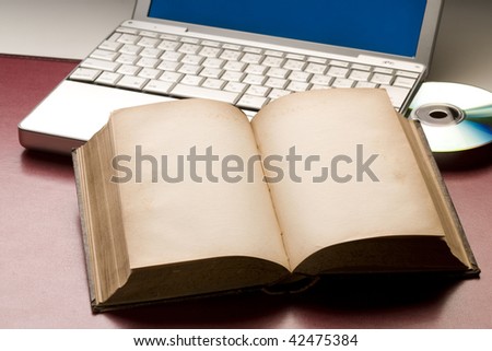 Old book opened to blank pages by laptop computer