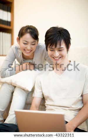 A happily young couple is watching PC together
