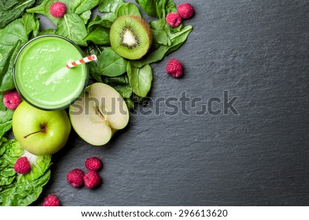 green smoothie with fruits and vegetables on black background