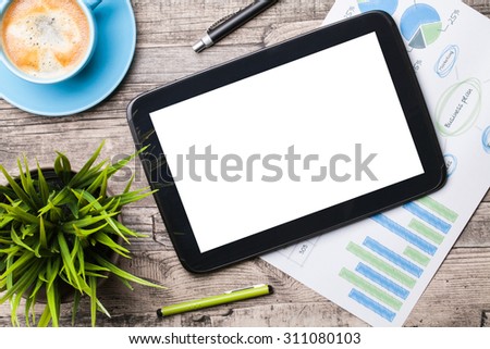 office table with a tablet, a coffee cup and a plant