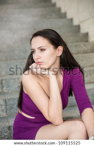 Outdoor portrait of young beautiful worried woman sitting on stairs - pensive mood