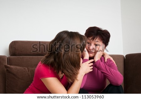 Daughter (young woman) comforts her depressed senior mother at home