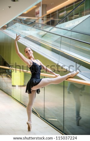 Ballet dancer (ballerina) dancing in modern shopping premises at escalator