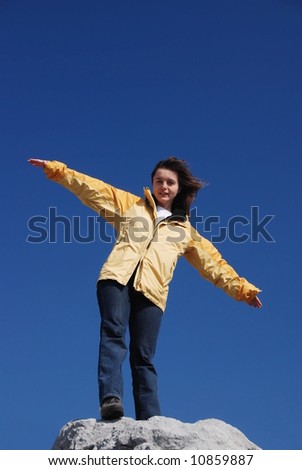 Young woman standing on rock enjoying life and wanting to fly
