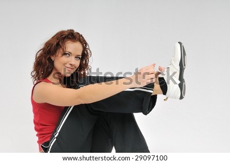 Young smiling sexy fitness woman in red and black ties lace on her shoe