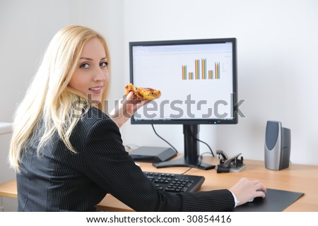 Young smiling business person working with computer eating pizza
