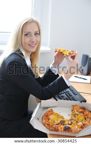 Young smiling business person on work place eating pizza