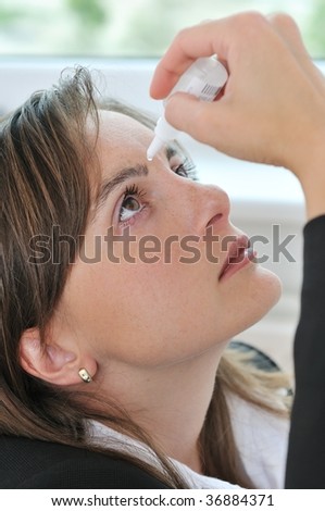 Eyes health care - detail of young woman applying eye drops