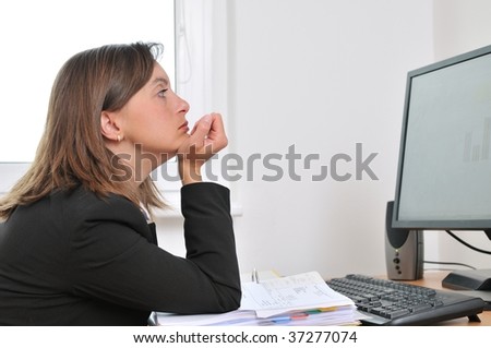 Tired and bored young business woman in depression sitting at computer on workplace