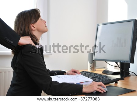 Business person (woman) on workplace with computer receiving neck massage from colleague (only hands visible)