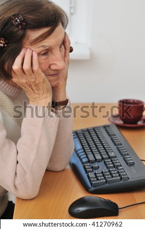 Indoors portrait of worried mature woman siting at computer