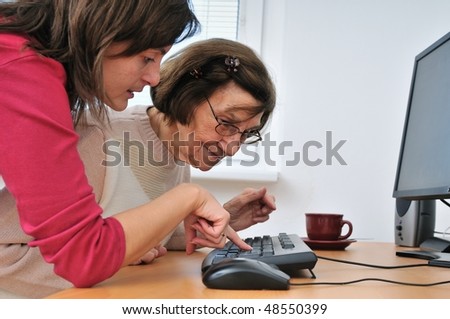 Young woman teaches her grandmother work with computer - senior lifestyle