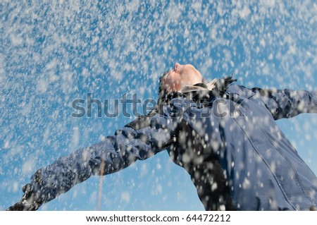 Young woman throwing snow on blue sky in background - joy and happines emotions