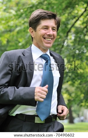 Escape from civilization - smiling senior business man running in park