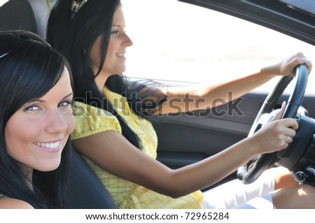 Youth lifestyle - two smiling friends (women) driving in car