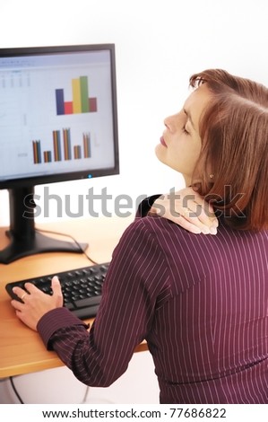 Business person with neck pain. Focus on hand on neck with blurred monitor on table in background.