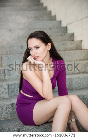 Outdoor portrait of young beautiful worried woman sitting on stairs - pensive mood