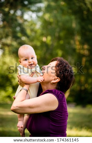 Grandmother with grandchild - senior woman holding her granddaughter outdoor in nature