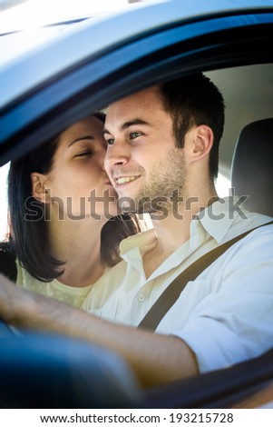 Couple in car - young woman kissing man in car while driving