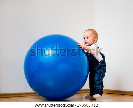Little baby is playing with big blue fit ball at home