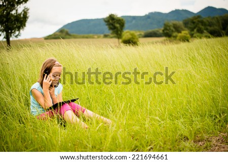 Smiling child watching movie on tablet outdoor in nature