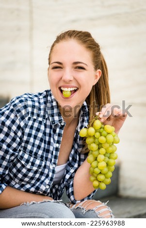 Young woman eating grapes outdoor - holding grape between teeth