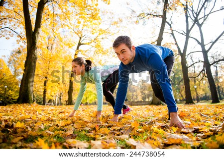 Young couple in steady position prepared for running in autumn nature