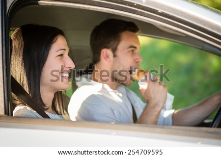 Couple in car - man driving and eating