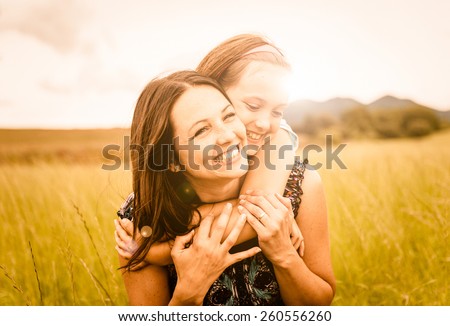 Mother and child are hugging and having fun outdoor in nature - photo with lens flare