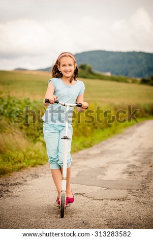 Beautiful girl driving scooter on rural road outdoor in nature