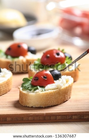 Preparing funny meal for children. Sandwiches in lady bird shape. Painting eyes on artificial lady bug\'s head.
