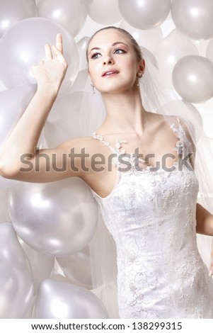 Beautiful bride in white dress in front of stunning decoration of thousands silver balloons