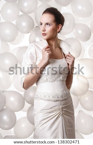 Beautiful bride, slim brunette in front of stunning decoration of thousands silver balloons.